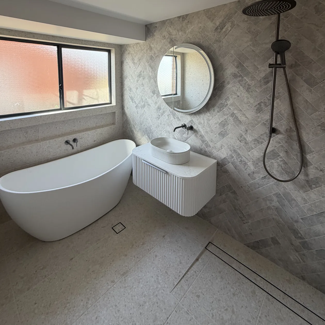 Finished bathroom with a wall hung vanity and tiled shower