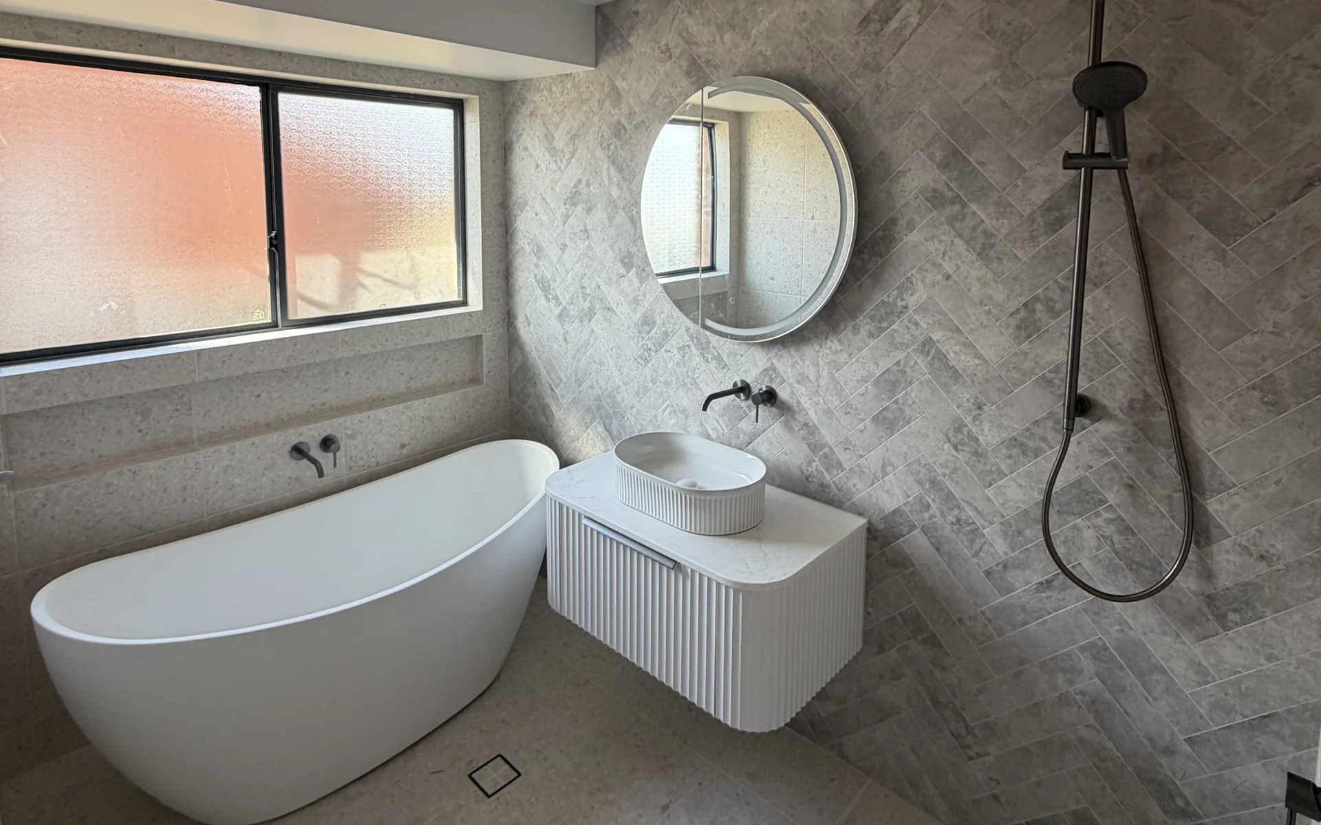 Finished bathroom with a freestanding bath, wall hung vanity and tiled shower