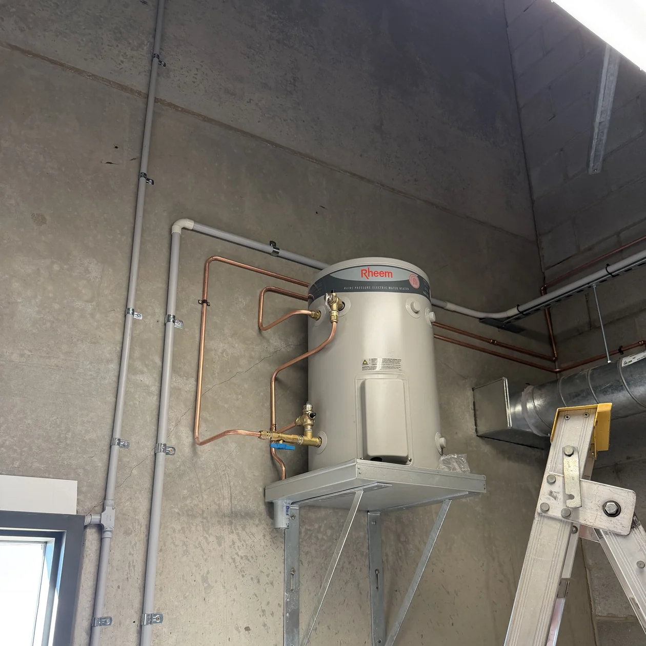 Hot water unit mounted on a bracket with copper pipework