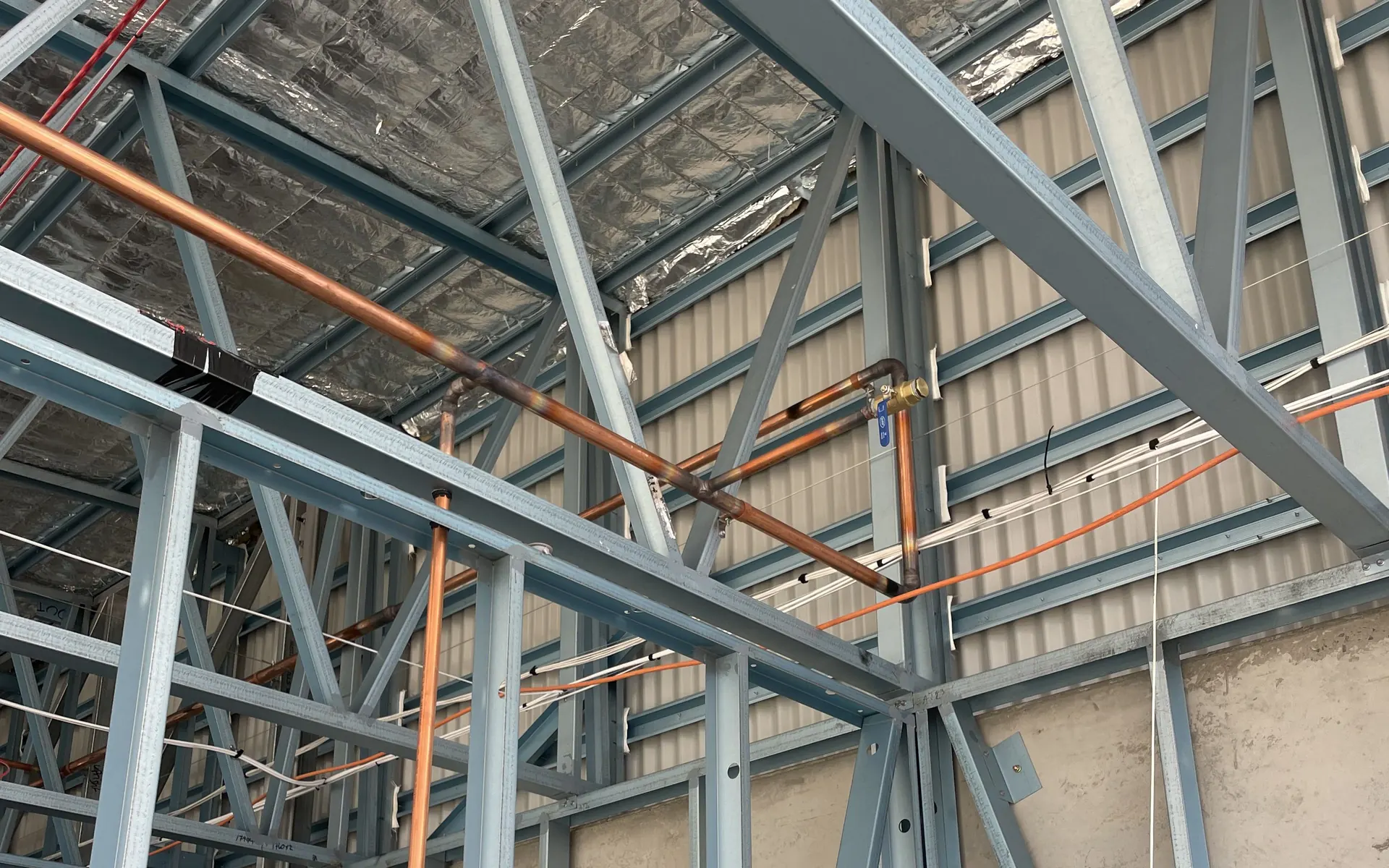 Copper pipework installed through a steel building frame
