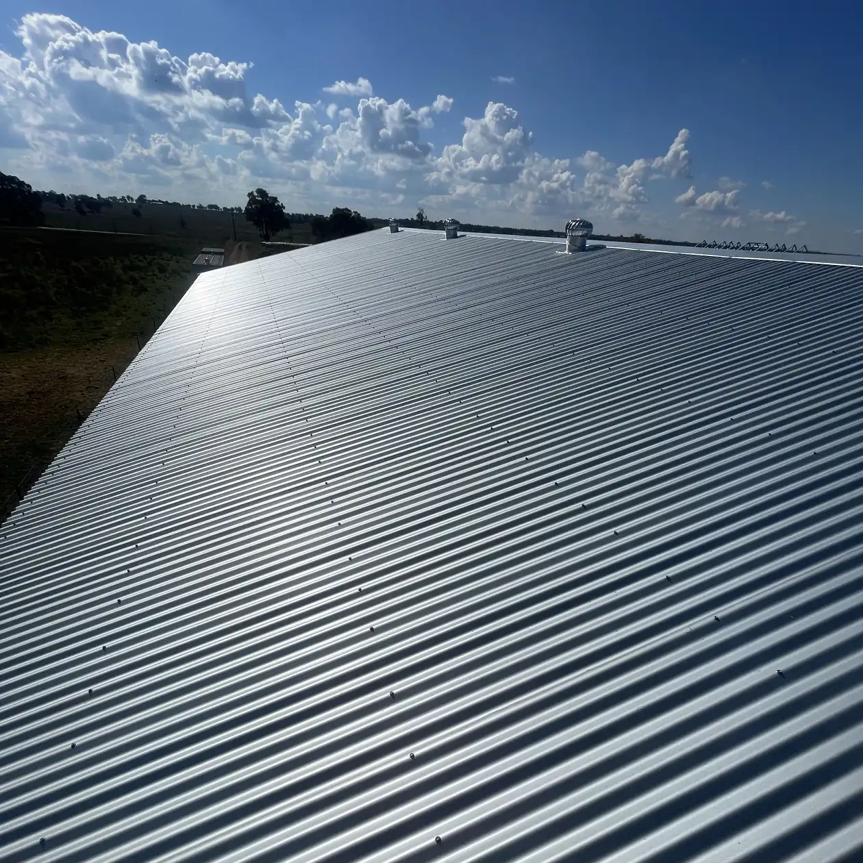 Large corrugated metal roof on a rural building under blue sky