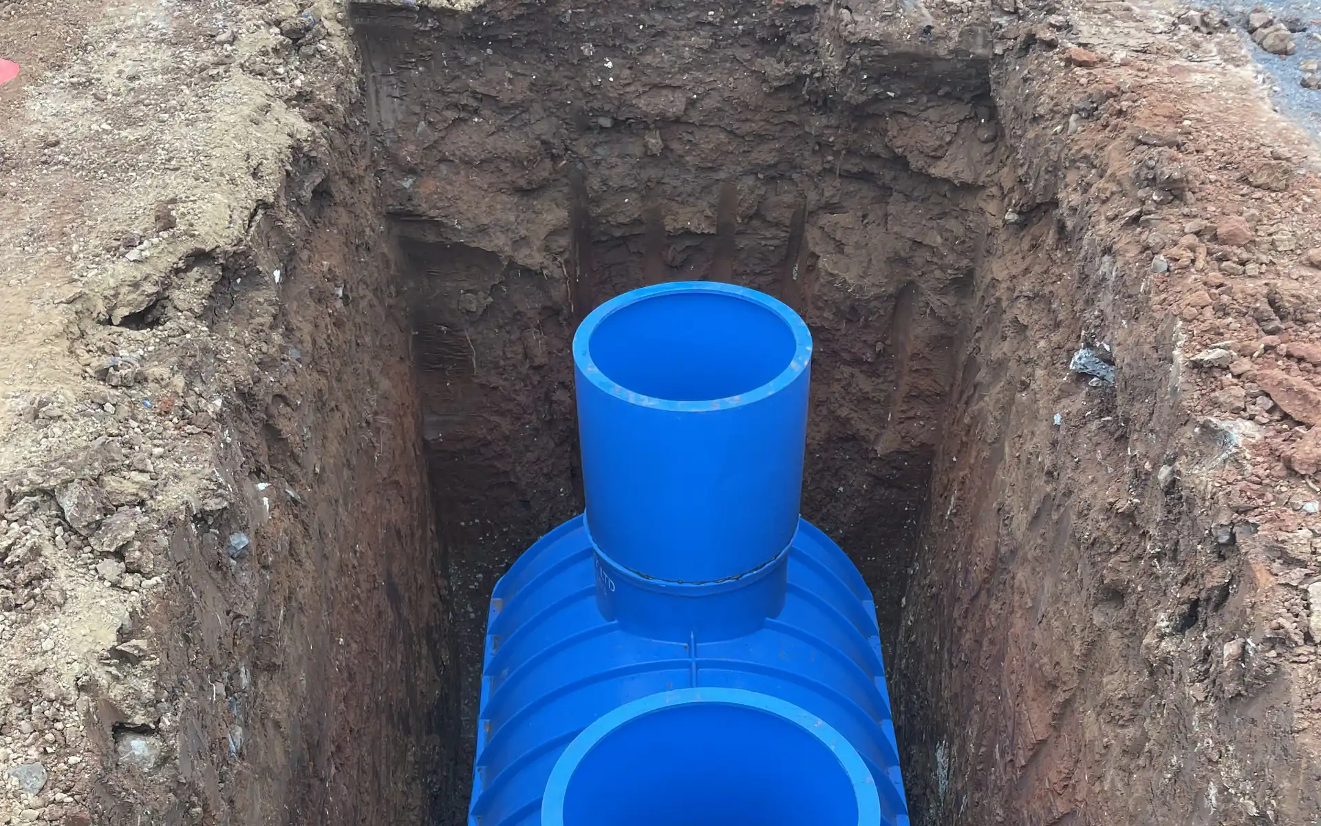 Drainage chamber installed in an open excavation with risers fitted