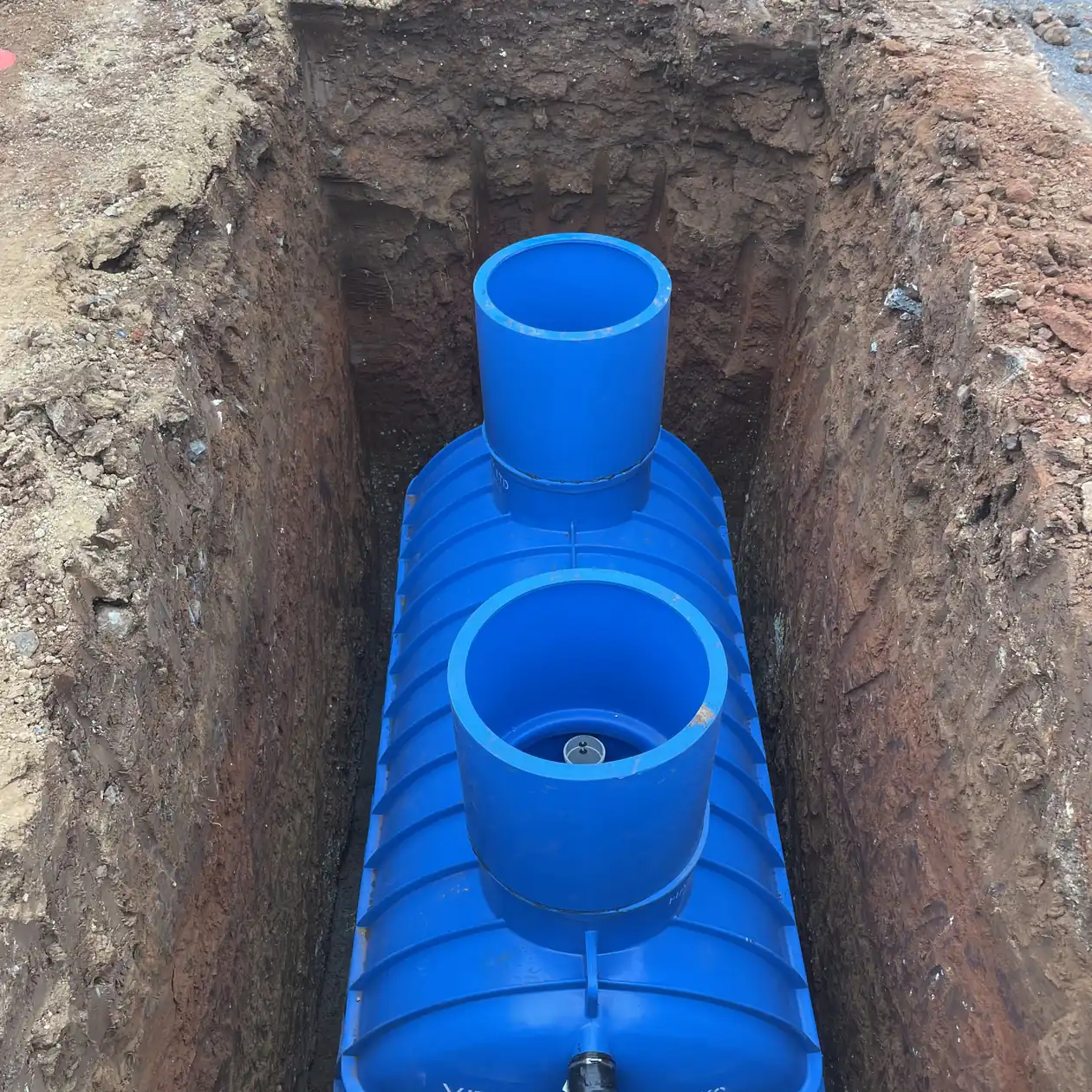 Drainage chamber installed in an open excavation with risers fitted