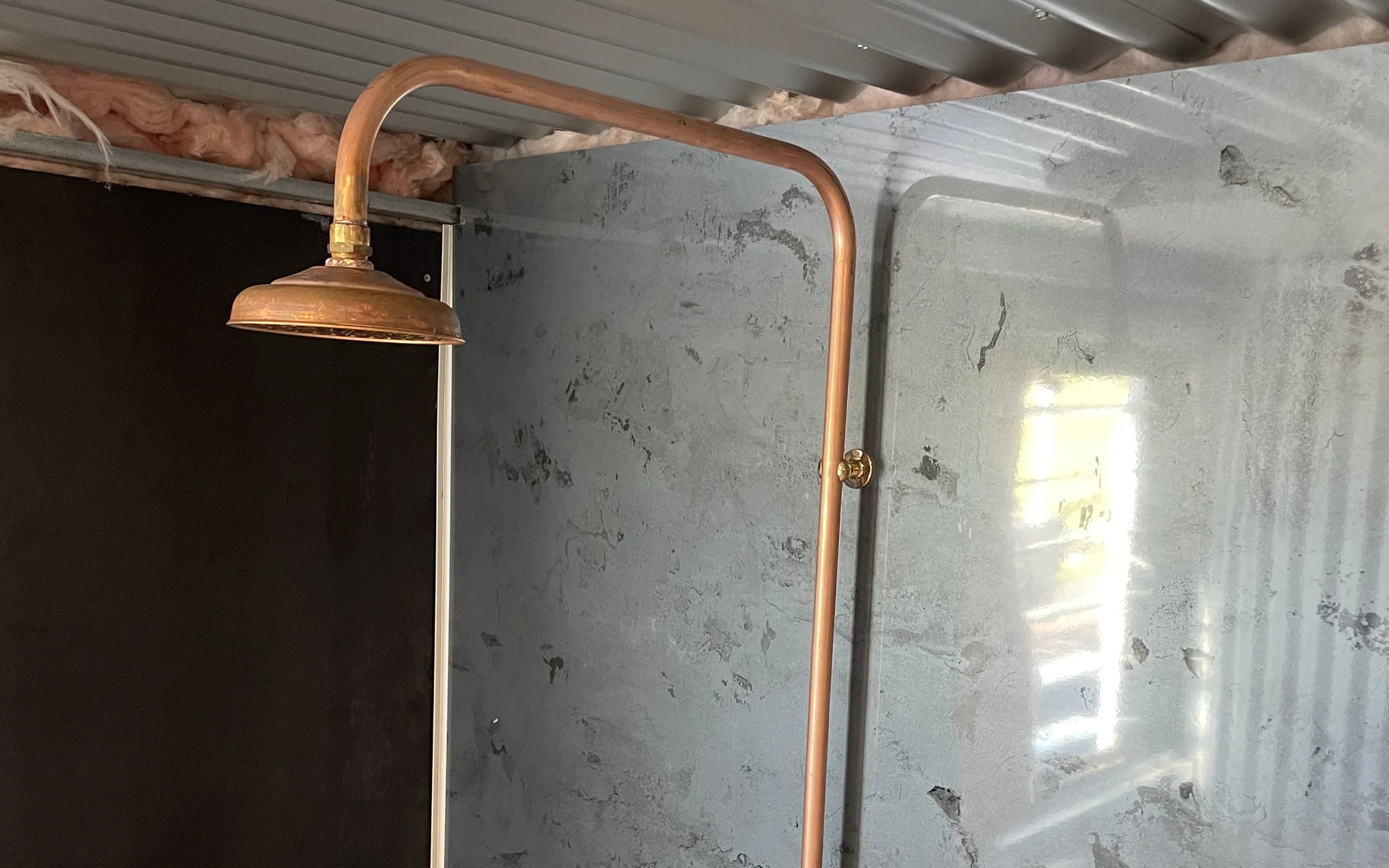 Exposed copper shower set and taps installed on a wall