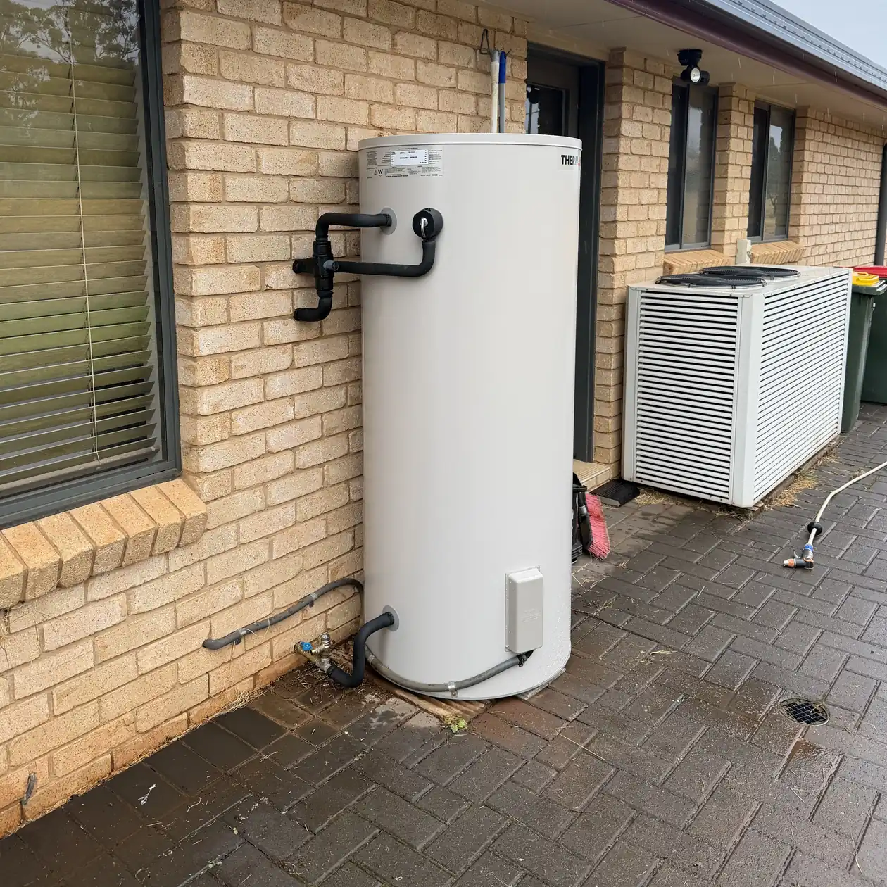 Storage hot water unit installed beside a brick house