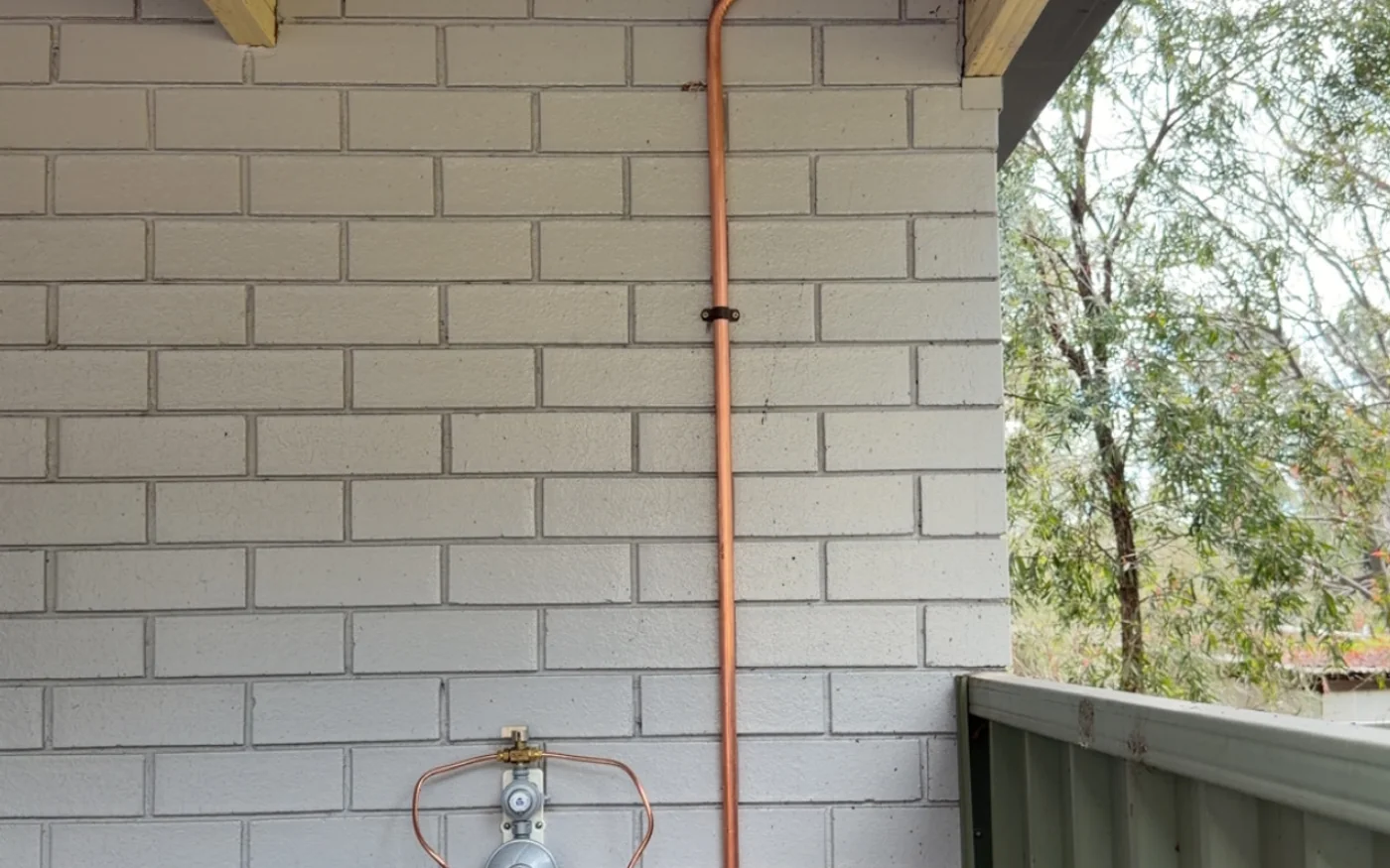 LPG bottle, regulator and copper gas pipework installed on a brick wall