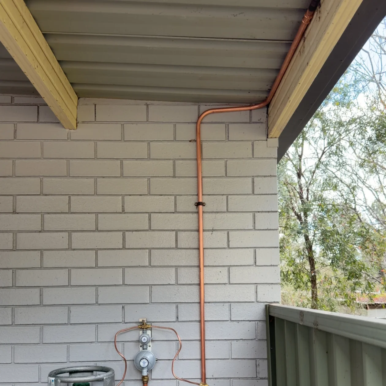LPG bottle and regulator with copper gas pipework running up a wall