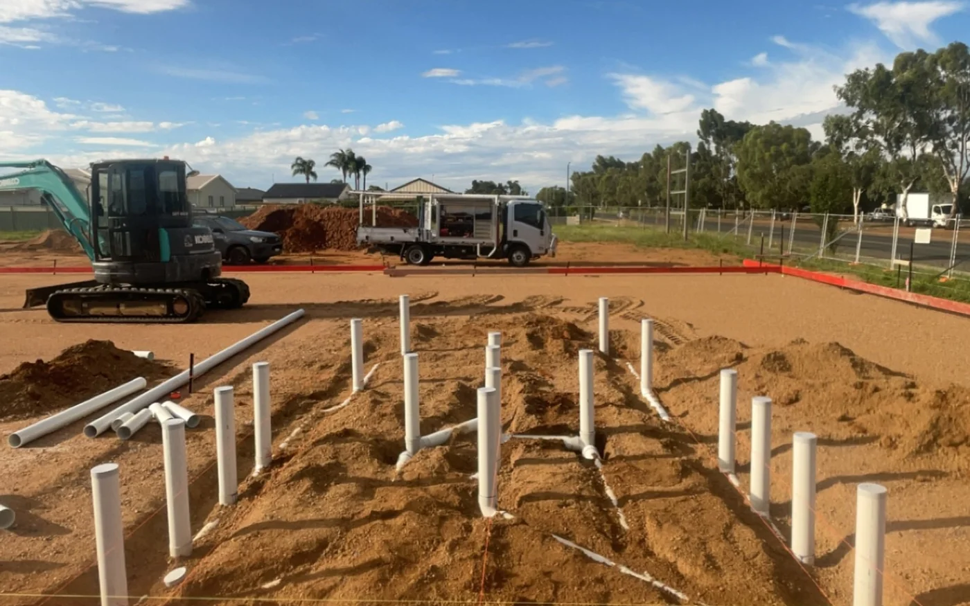 Sanitary drainage roughed in on a new home site with an excavator and work truck