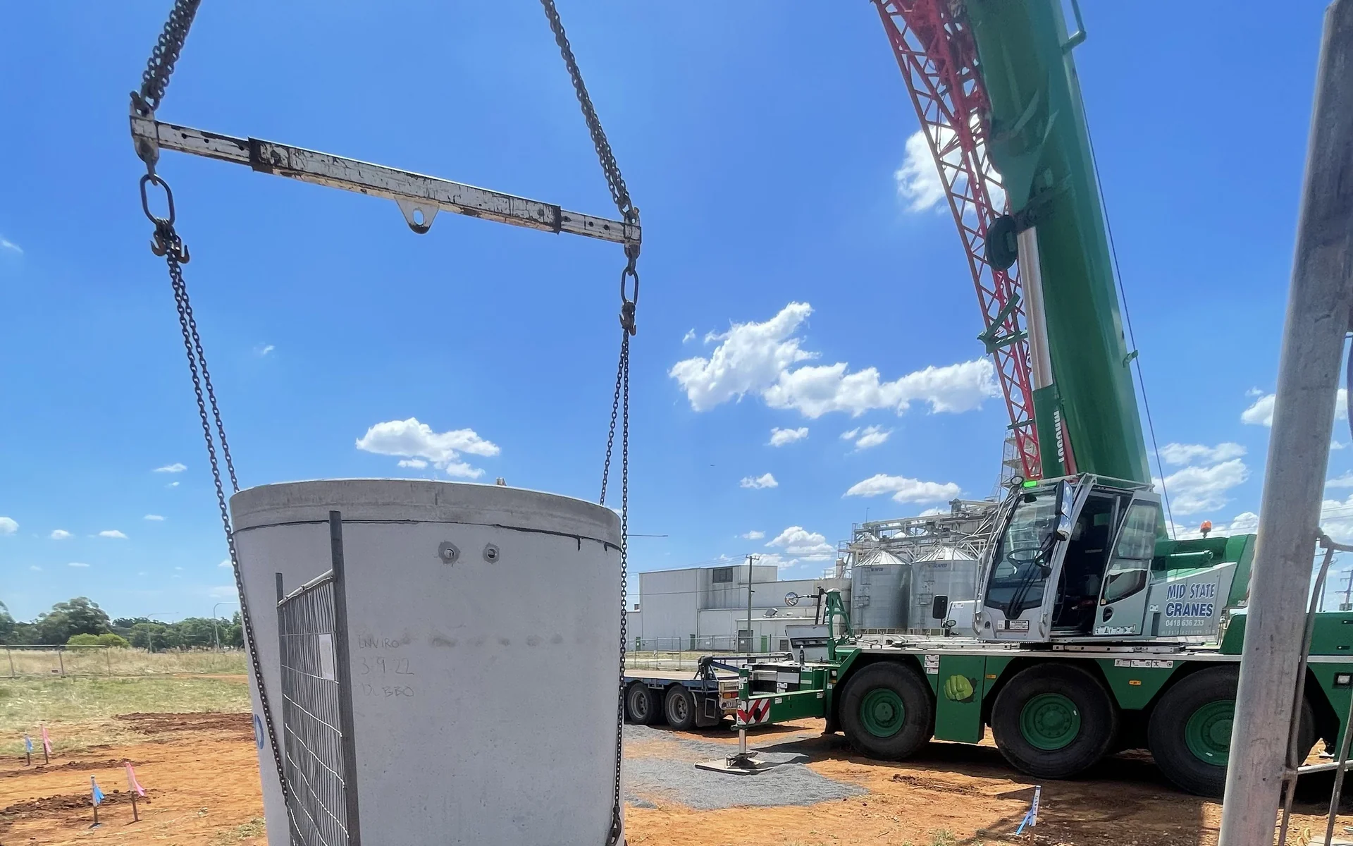 Precast concrete manhole being lifted into an excavation by crane