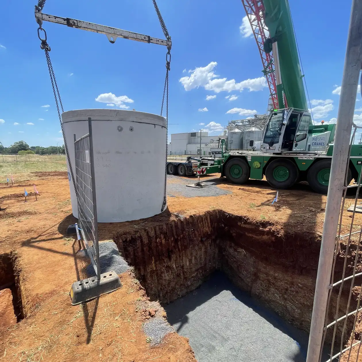 Precast concrete manhole being craned into a prepared excavation
